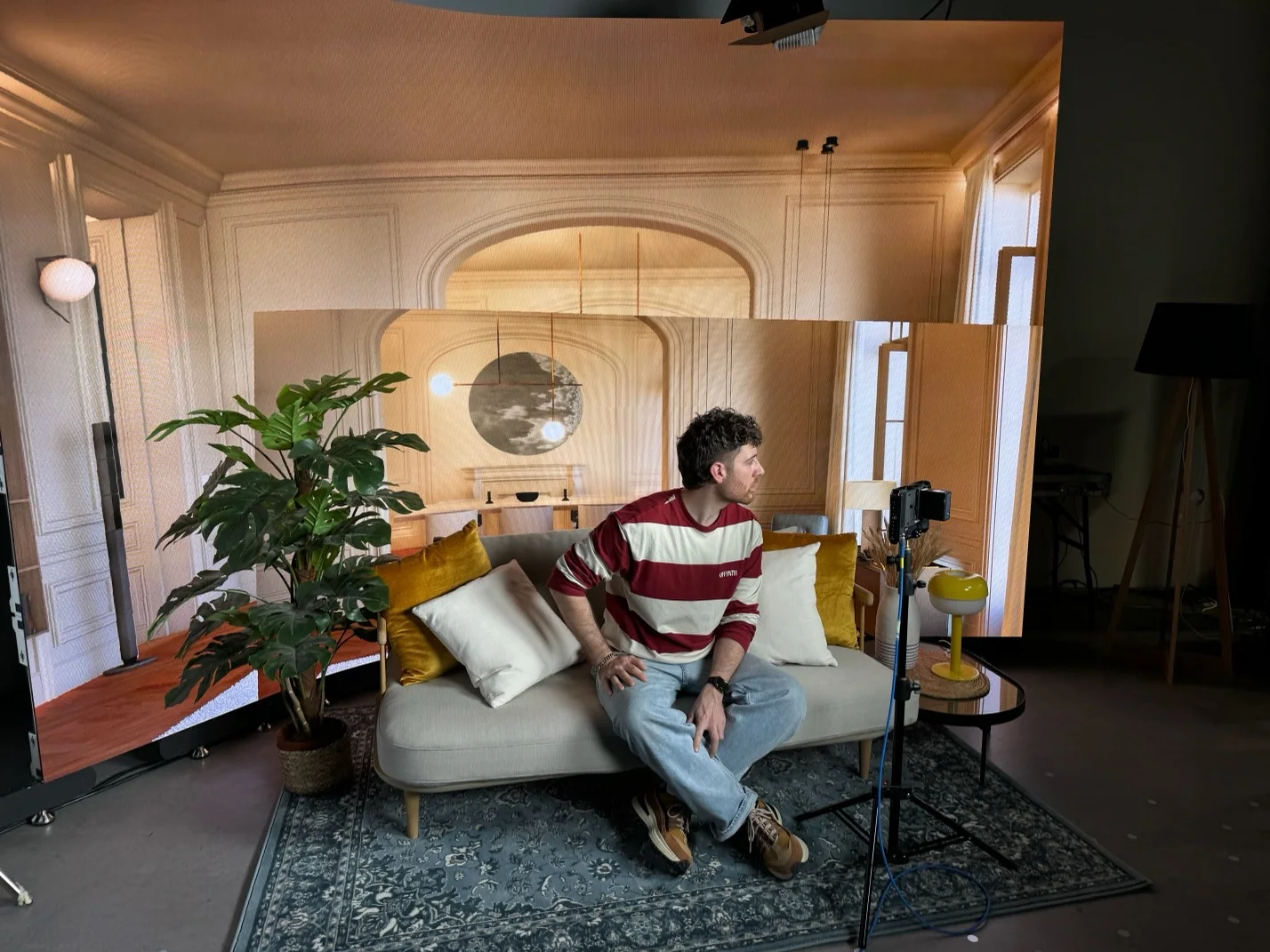 A presenter on a living-room set inside the studio.