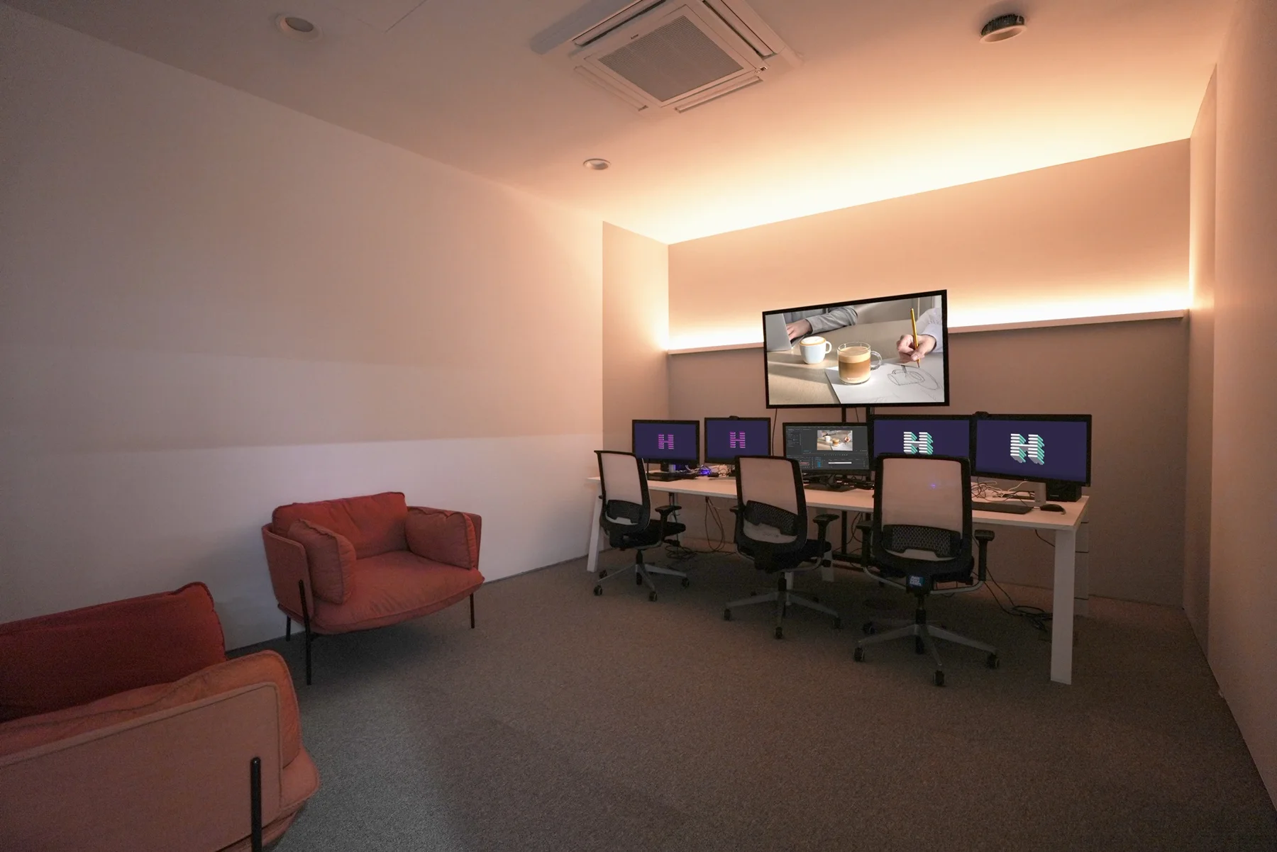 Edit suite with warm lighting and three workstations.