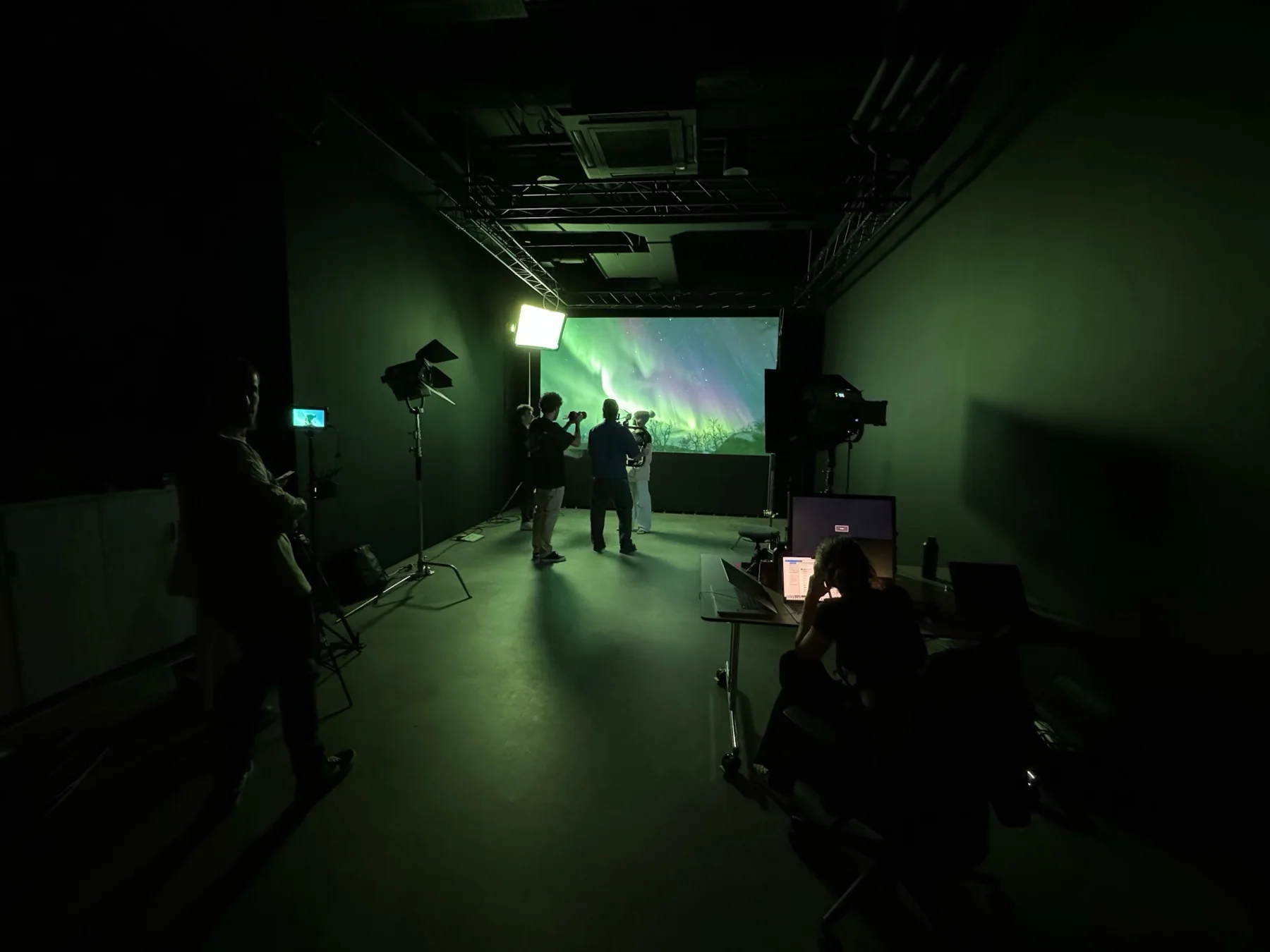 A crew filming in the green-screen virtual studio, with an aurora projected on the LED wall.